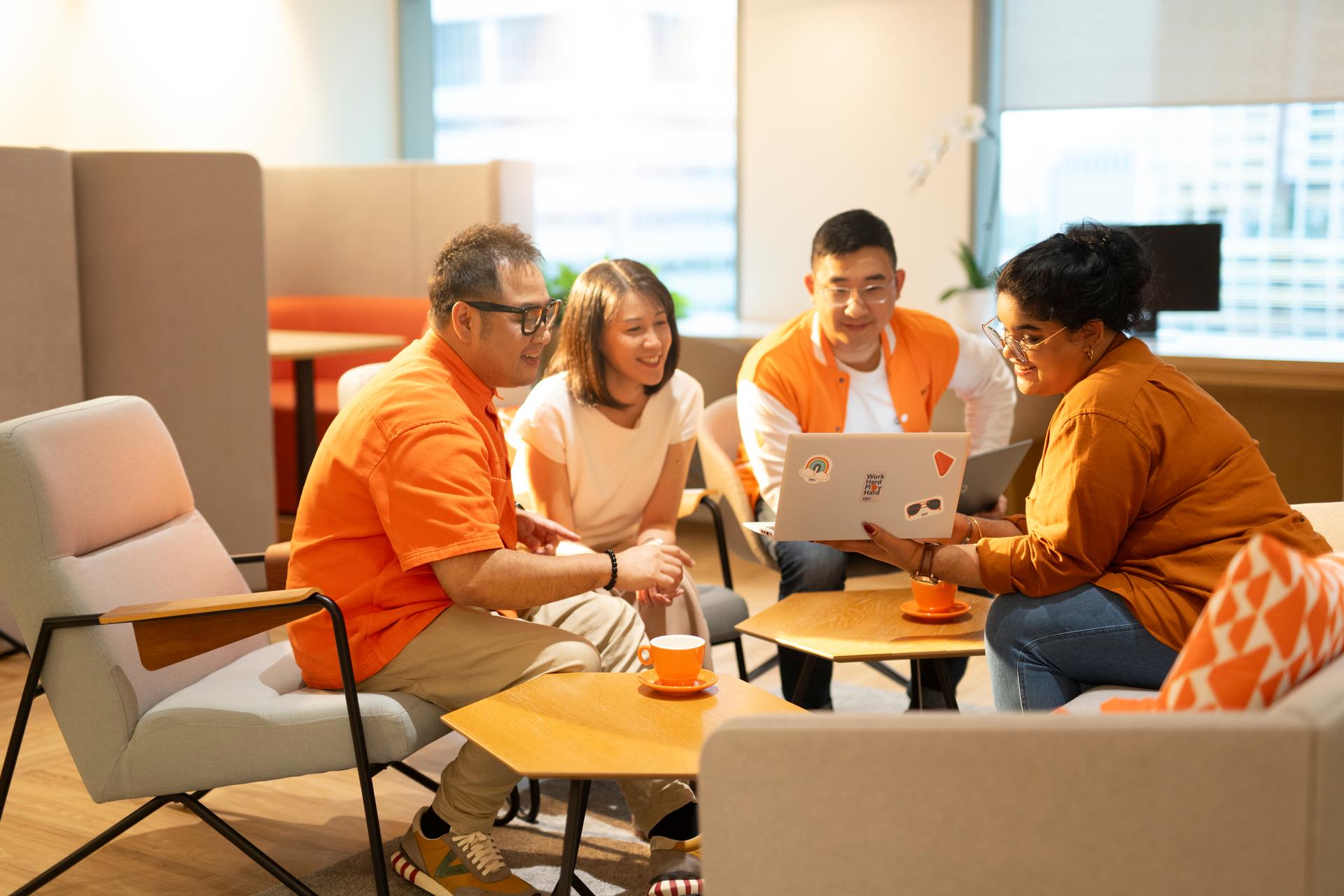 Alt text: A group of colleagues discussing work at the office lounge in the evening