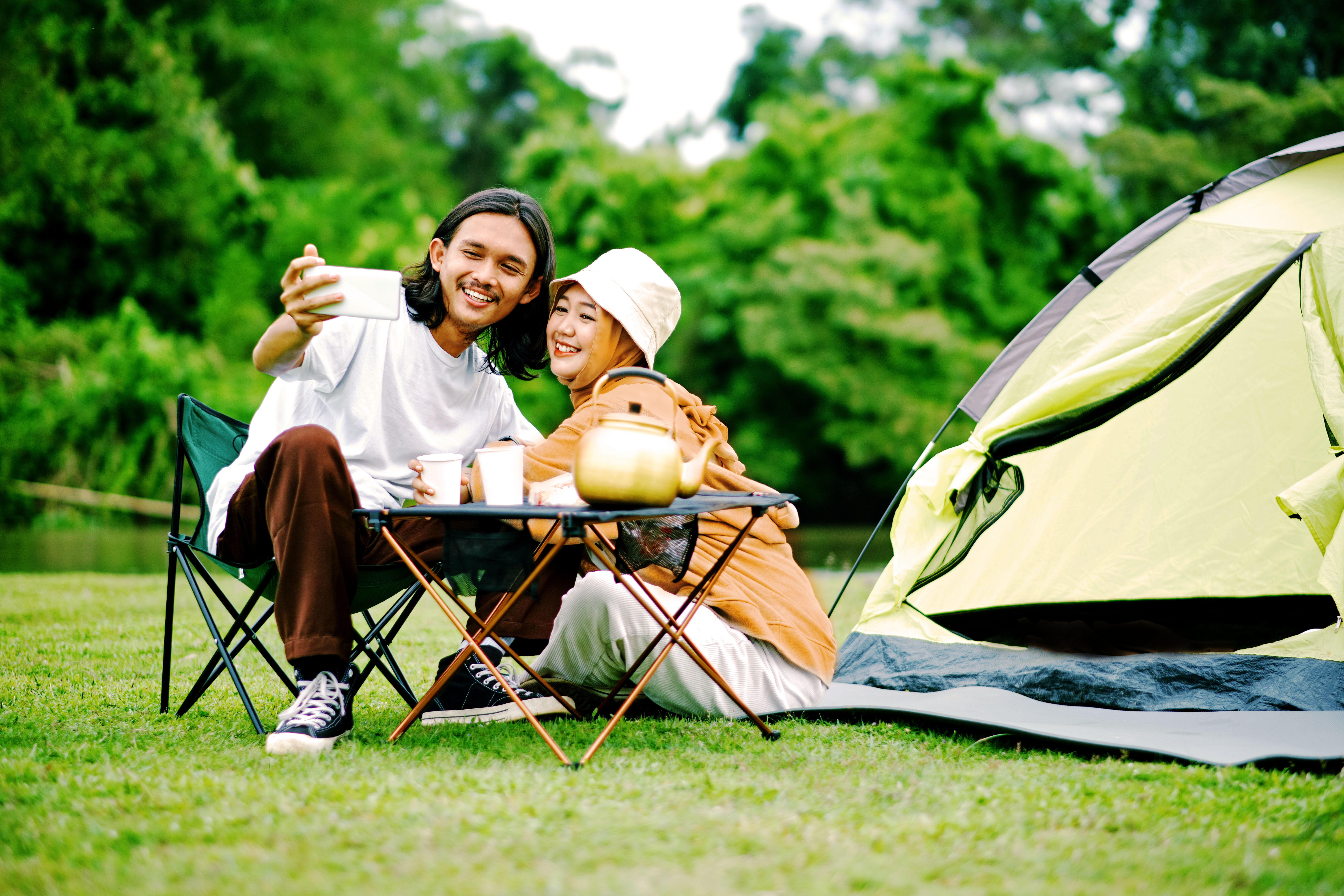 Couple taking a selfie outside a tent during camping.
