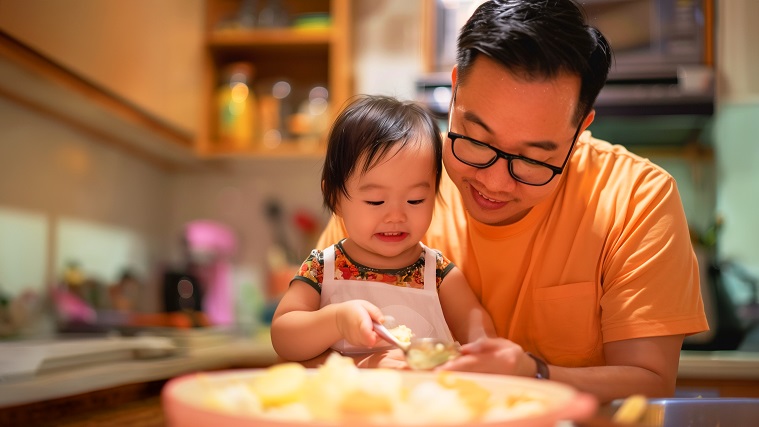 Father preparing food with young daughter in the kitchen
