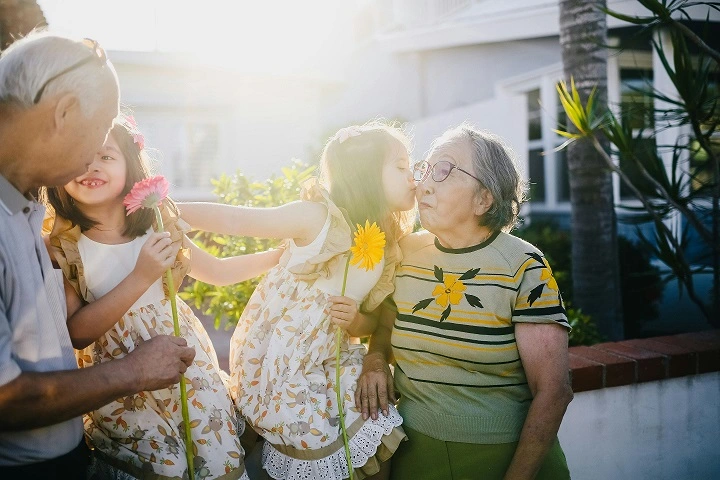 An image of two little girls and their grandparents in their garden.
