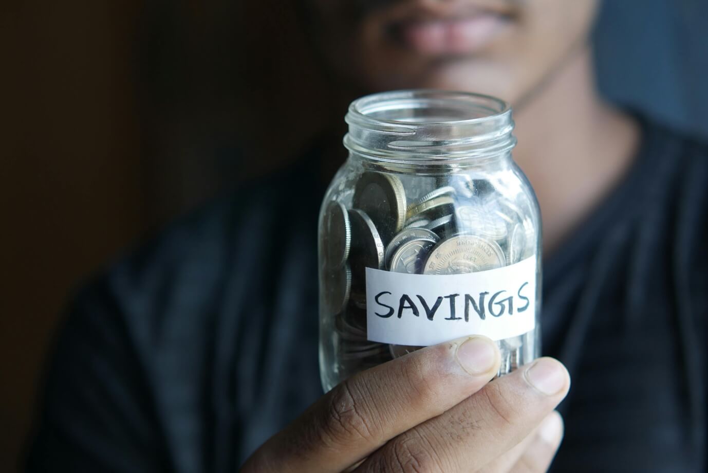 Close-up shot of a person holding a jar with coins