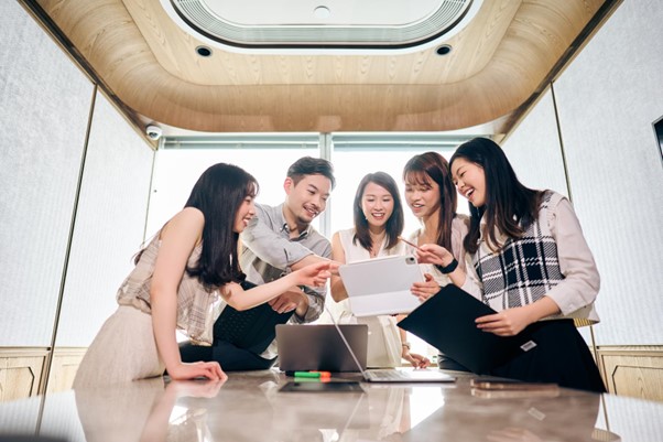 A group of employees huddled around a meeting table