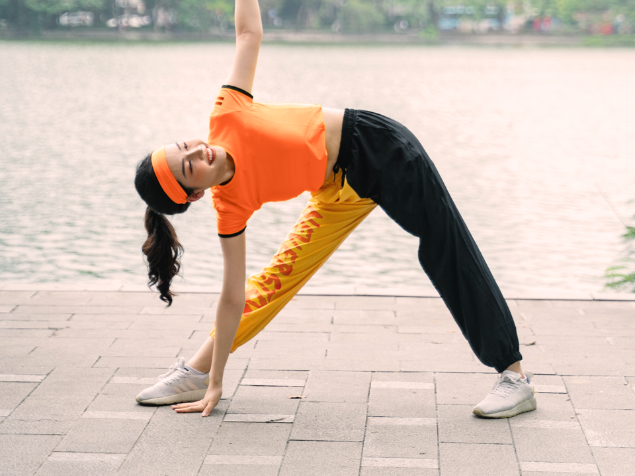 Woman in an orange shirt and bandana works out by the river