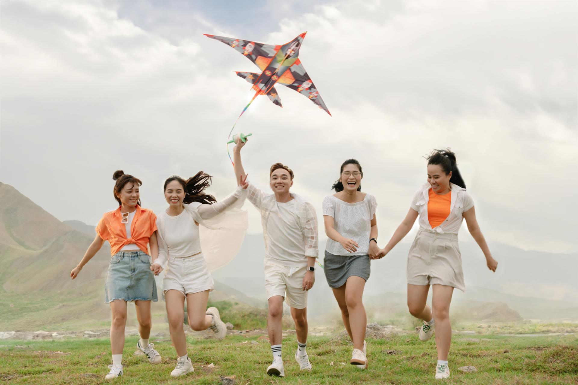 Group of friends flying a kite on an open field