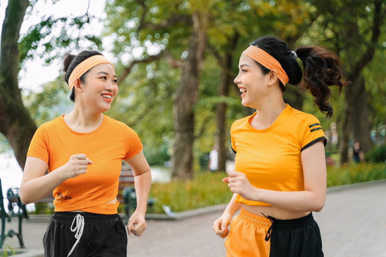 Two women friends jogging outdoors in the park