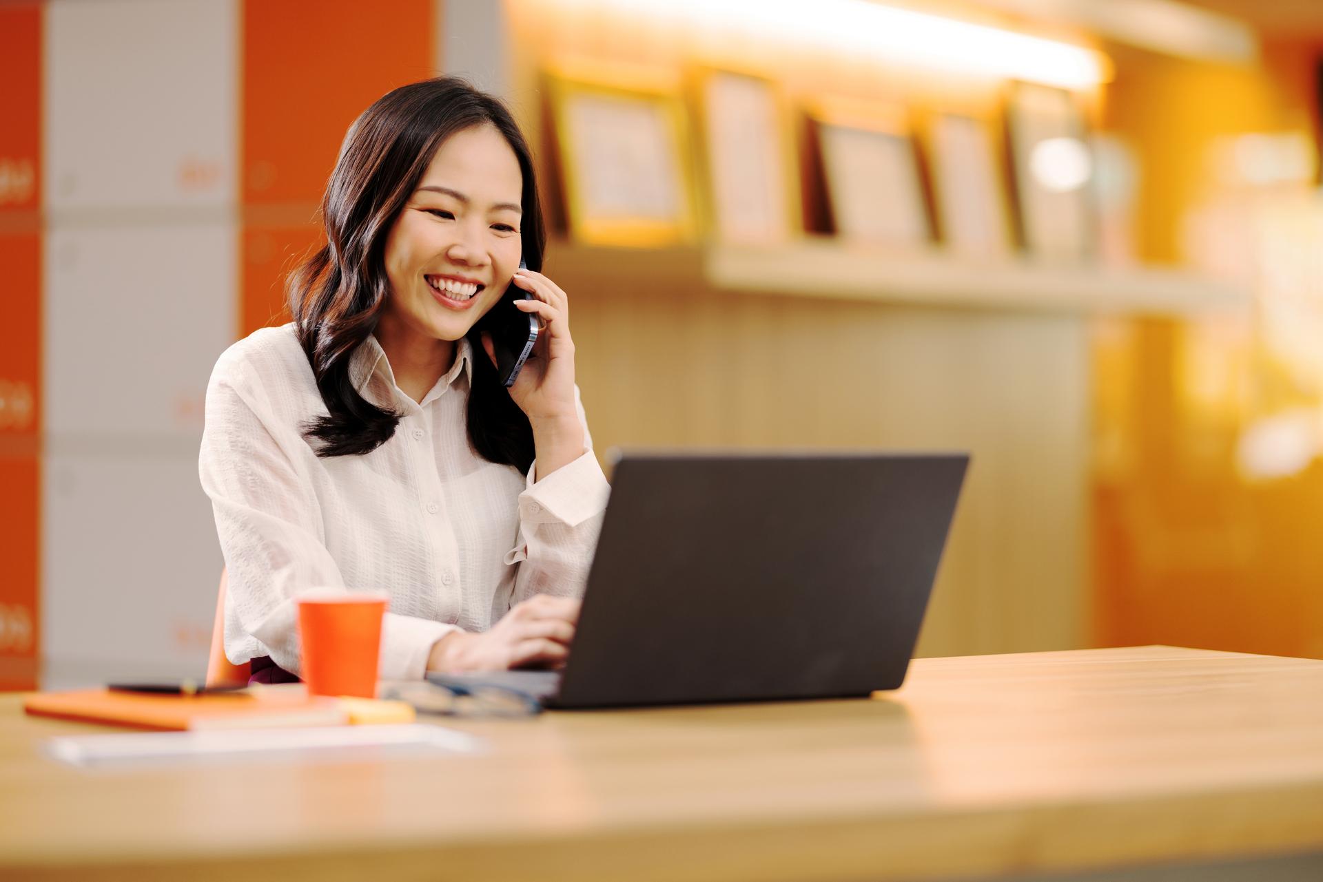 Woman calls someone while she's on her laptop