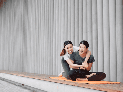 Two friends hugging on a yoga mat